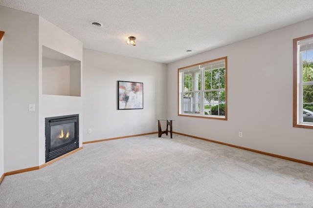 10612 172nd Ln NW, Elk River, MN 55330 - unfurnished living room featuring carpet floors, healthy amount of natural light, baseboards, a textured ceiling, and a glass covered fireplace