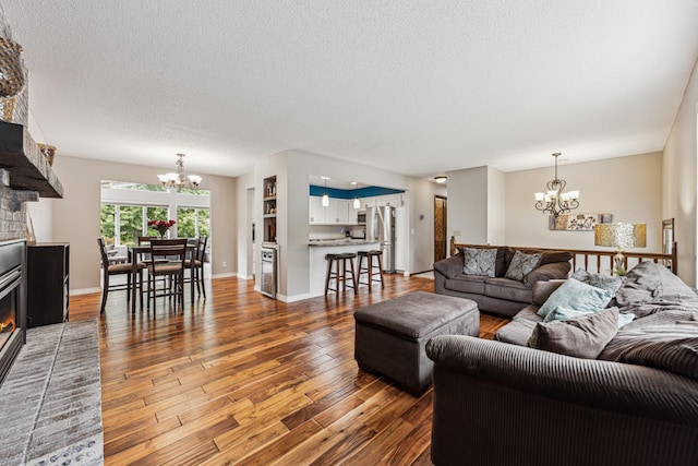 11788 65th Pl N, Maple Grove, MN 55369 - living room with a chandelier, a fireplace, wood finished floors, a textured ceiling, and baseboards