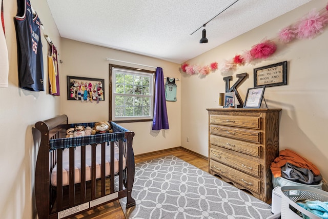 11788 65th Pl N, Maple Grove, MN 55369 - bedroom featuring a textured ceiling, track lighting, wood finished floors, and baseboards