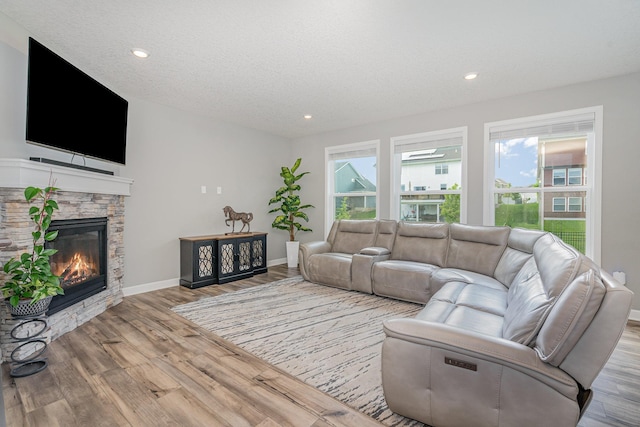 6016 Inskip Ave S, Cottage Grove, MN 55016 - living room featuring wood finished floors, baseboards, a stone fireplace, recessed lighting, and a textured ceiling