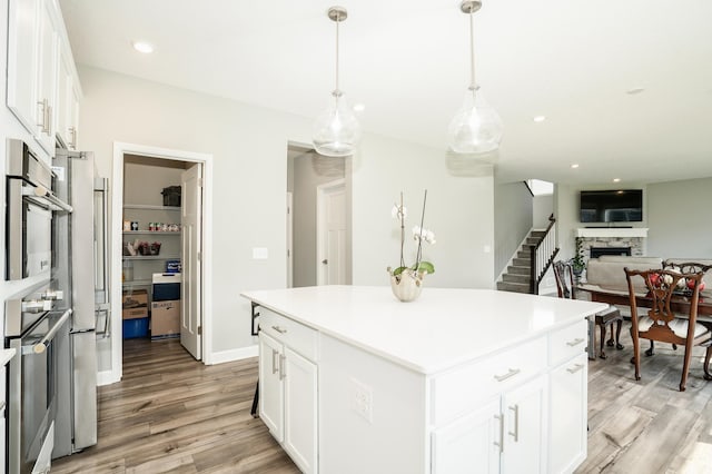 6016 Inskip Ave S, Cottage Grove, MN 55016 - kitchen with light wood-style flooring, a fireplace, white cabinets, stainless steel oven, and a center island