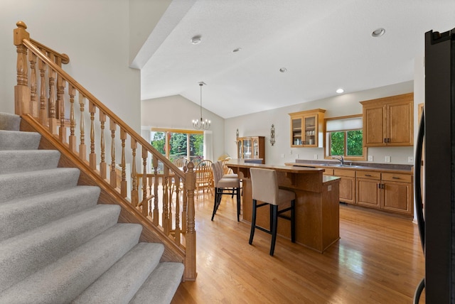 2554 160th Ave NE, Ham Lake, MN 55304 - kitchen featuring a kitchen breakfast bar, freestanding refrigerator, a sink, glass insert cabinets, and light wood-style floors