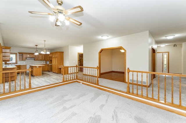 2310 Wilshire Ln NE, Rochester, MN 55906 - unfurnished living room featuring ceiling fan, arched walkways, light carpet, and a chandelier