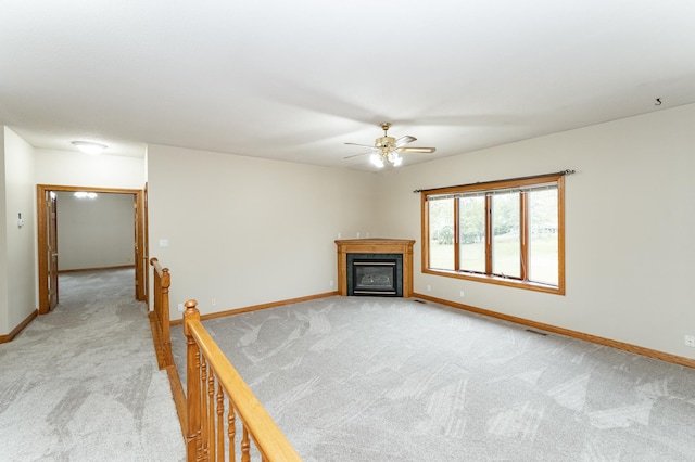2310 Wilshire Ln NE, Rochester, MN 55906 - unfurnished living room with light carpet, a ceiling fan, baseboards, and a glass covered fireplace