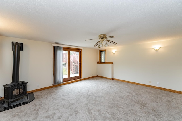 2310 Wilshire Ln NE, Rochester, MN 55906 - unfurnished living room featuring a ceiling fan, carpet floors, a wood stove, and baseboards
