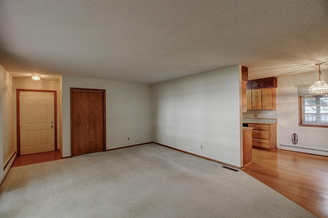 14070 County 18, Park Rapids, MN 56470 - unfurnished living room with a baseboard radiator, light carpet, baseboards, a textured ceiling, and light wood-type flooring