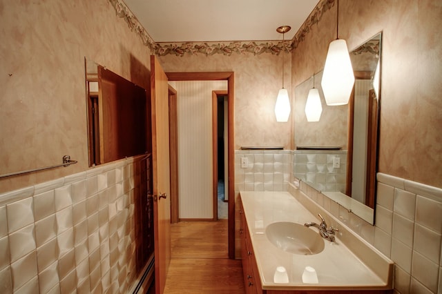 14070 County 18, Park Rapids, MN 56470 - bathroom featuring tile walls, wood finished floors, vanity, a wainscoted wall, and wallpapered walls
