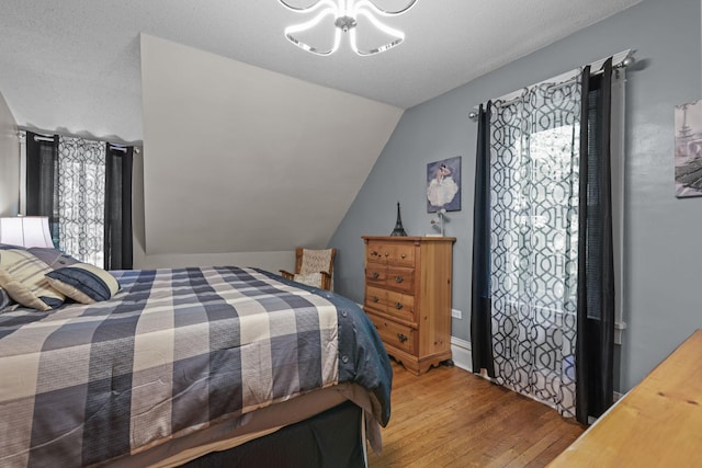 35301 Lily St NW, Springvale Twp, MN 55008 - bedroom with a chandelier, wood finished floors, and vaulted ceiling