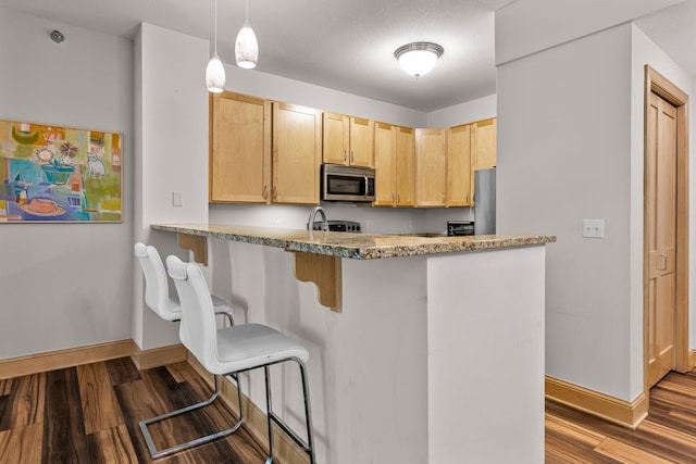 620 Main St N Unit 412, Stillwater, MN 55082 - kitchen with stainless steel microwave, light brown cabinetry, a peninsula, dark wood-type flooring, and refrigerator