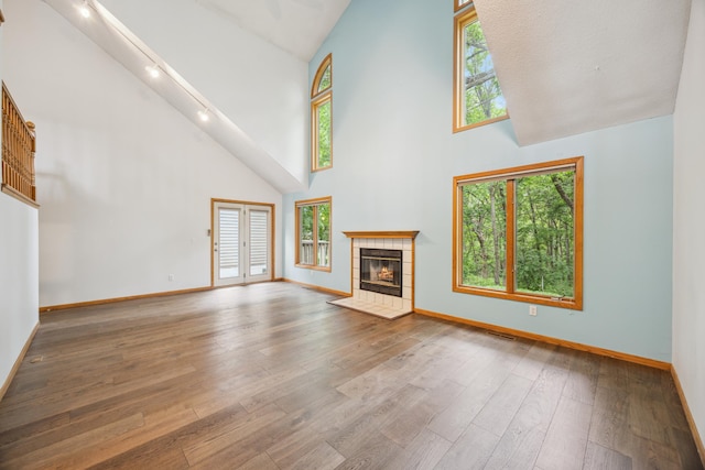 7813 111th St, Bloomington, MN 55438 - unfurnished living room with high vaulted ceiling, rail lighting, a tiled fireplace, hardwood / wood-style flooring, and plenty of natural light