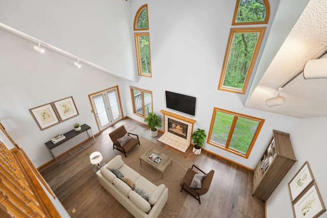7813 111th St, Bloomington, MN 55438 - living area with track lighting, a towering ceiling, a tiled fireplace, and hardwood / wood-style flooring