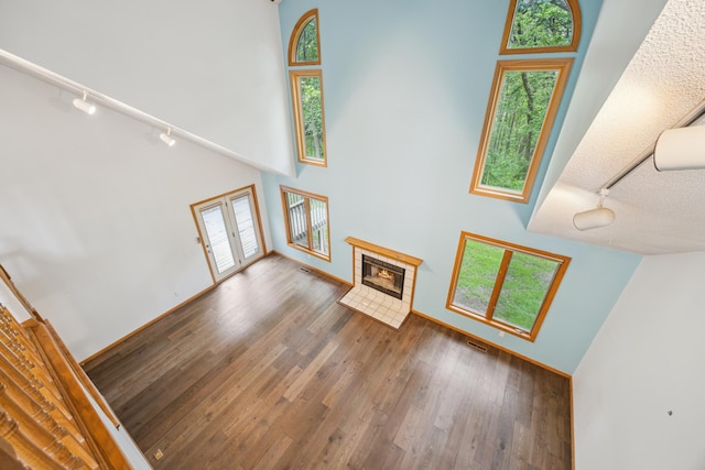 7813 111th St, Bloomington, MN 55438 - unfurnished living room with rail lighting, a towering ceiling, healthy amount of natural light, and a tiled fireplace