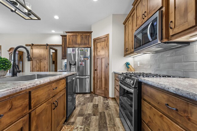 5855 281st Ave NW, Spencer Brook Twp, MN 55040 - kitchen featuring appliances with stainless steel finishes, a sink, a barn door, dark wood finished floors, and backsplash