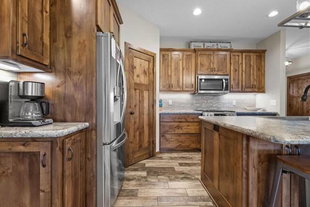 5855 281st Ave NW, Spencer Brook Twp, MN 55040 - kitchen with appliances with stainless steel finishes, light wood finished floors, tasteful backsplash, a sink, and brown cabinets