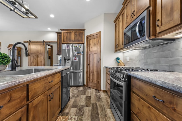 5855 281st Ave NW, Spencer Brook Twp, MN 55040 - kitchen featuring stainless steel appliances, a barn door, dark wood-type flooring, tasteful backsplash, and recessed lighting