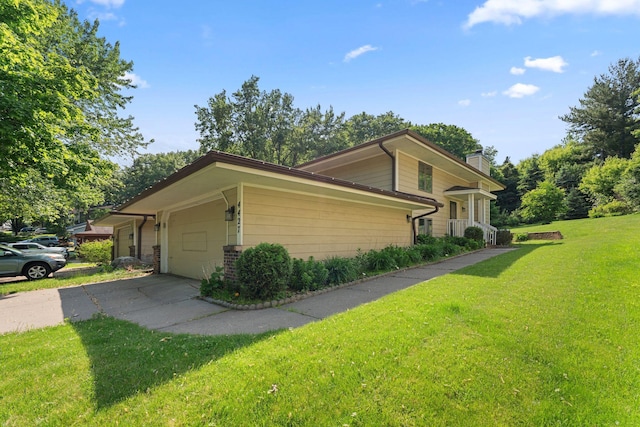 4427 Chatsworth St N, Shoreview, MN 55126 - view of side of property featuring concrete driveway, a yard, a garage, and a chimney