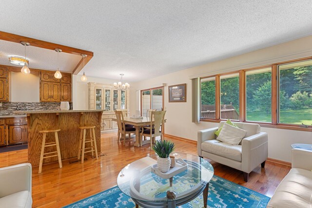 4427 Chatsworth St N, Shoreview, MN 55126 - living room with a chandelier, a textured ceiling, light wood-style flooring, and baseboards