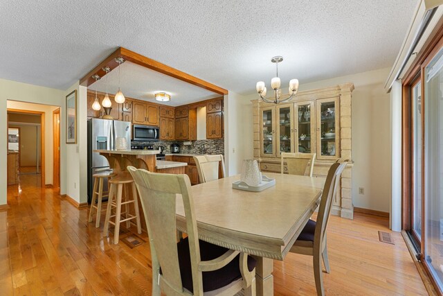 4427 Chatsworth St N, Shoreview, MN 55126 - dining space featuring a chandelier, light wood-type flooring, baseboards, and a textured ceiling