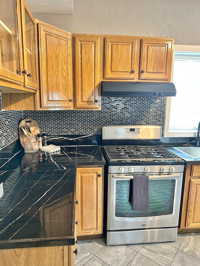 803 Jefferson Ave, Albert Lea, MN 56007 - kitchen featuring gas range, decorative backsplash, dark countertops, and exhaust hood