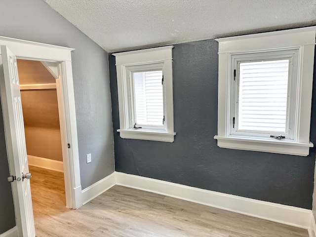 803 Jefferson Ave, Albert Lea, MN 56007 - unfurnished room with light wood-style flooring, a textured ceiling, vaulted ceiling, a textured wall, and baseboards