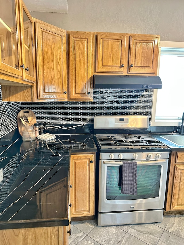 803 Jefferson Ave, Albert Lea, MN 56007 - kitchen with gas range, under cabinet range hood, backsplash, and dark countertops