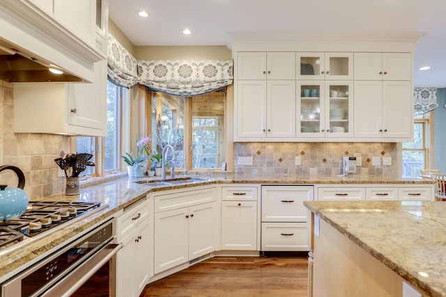 10025 Adam Ave, Inver Grove Heights, MN 55077 - kitchen with wall oven, custom exhaust hood, white cabinetry, light wood-style flooring, and glass insert cabinets