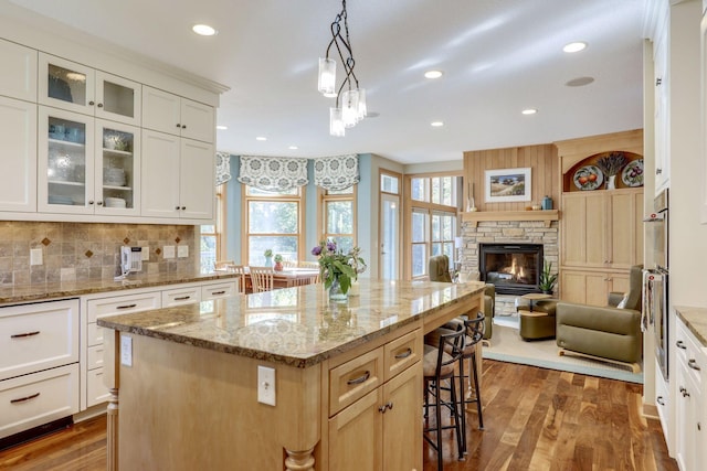 10025 Adam Ave, Inver Grove Heights, MN 55077 - kitchen with open floor plan, a kitchen breakfast bar, wood finished floors, glass insert cabinets, and recessed lighting
