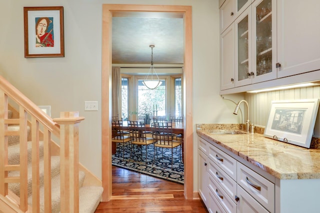 10025 Adam Ave, Inver Grove Heights, MN 55077 - kitchen featuring wood finished floors, white cabinetry, light stone countertops, and glass insert cabinets