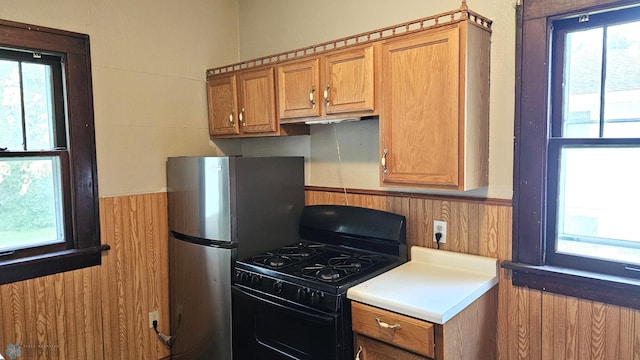 1602 11th St N, Fargo, ND 58102 - kitchen with black gas range, healthy amount of natural light, a wainscoted wall, brown cabinetry, and light countertops