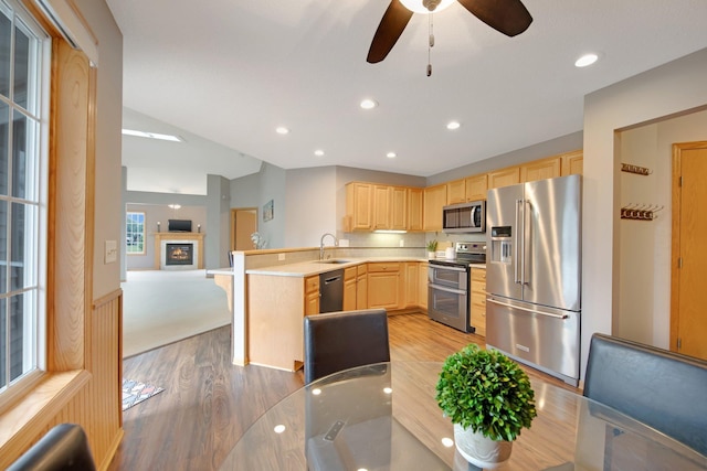 6103 150th St N, Hugo, MN 55038 - kitchen with stainless steel appliances, light brown cabinetry, light wood finished floors, a peninsula, and open floor plan