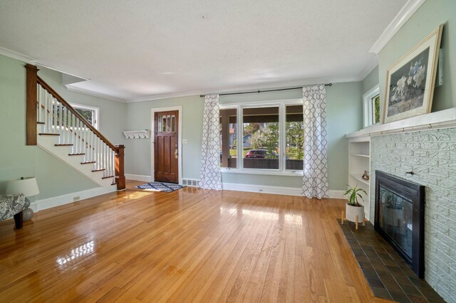 5232 Tioga St, Duluth, MN 55804 - unfurnished living room with hardwood / wood-style floors, stairs, a fireplace, crown molding, and baseboards