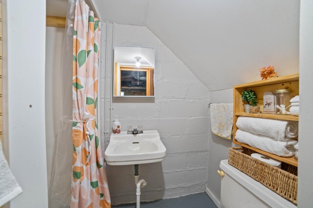 5232 Tioga St, Duluth, MN 55804 - full bathroom featuring lofted ceiling, a sink, concrete block wall, toilet, and a shower with shower curtain