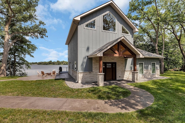 565 Brooks Lake Rd NW, Cokato, MN 55321 - view of front of property with board and batten siding, stone siding, a patio, a front lawn, and a water view