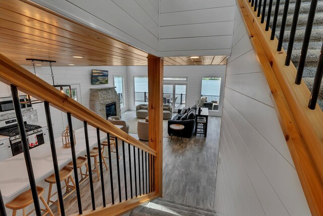 565 Brooks Lake Rd NW, Cokato, MN 55321 - stairs featuring plenty of natural light, a fireplace, wood finished floors, wooden walls, and wooden ceiling