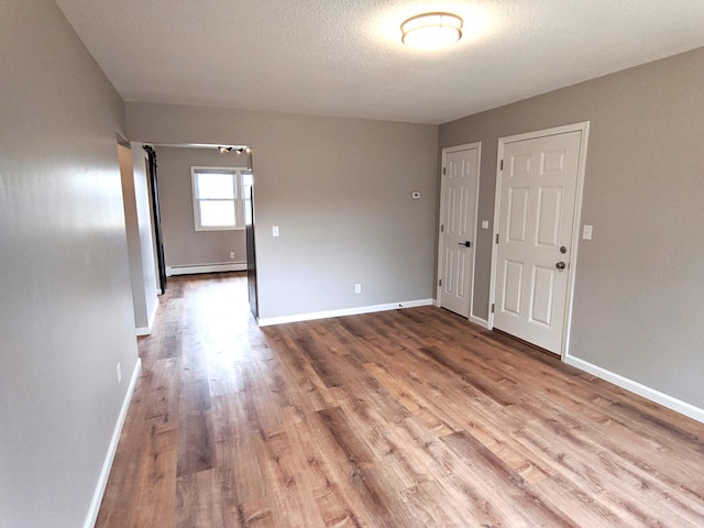 1101 Spring Creek Rd, Northfield, MN 55057 - unfurnished room with baseboard heating, wood finished floors, baseboards, and a textured ceiling