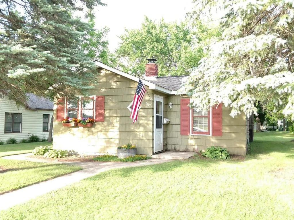 1117 7th St SW, Willmar, MN 56201 - view of front of house with a chimney, a front lawn, and a shingled roof