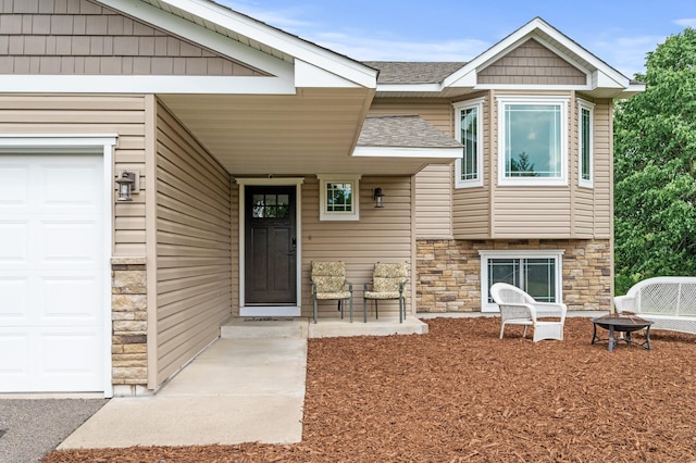 18125 Fillmore St NE, East Bethel, MN 55011 - view of exterior entry with stone siding, roof with shingles, and an attached garage