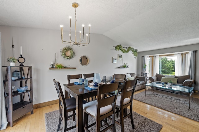 18125 Fillmore St NE, East Bethel, MN 55011 - dining space featuring light wood-type flooring, a chandelier, vaulted ceiling, and a textured ceiling
