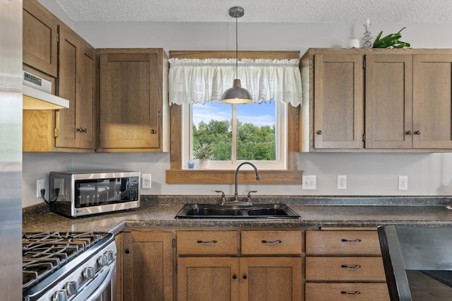 18125 Fillmore St NE, East Bethel, MN 55011 - kitchen featuring appliances with stainless steel finishes, dark countertops, a textured ceiling, under cabinet range hood, and hanging light fixtures