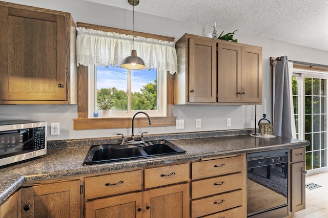 18125 Fillmore St NE, East Bethel, MN 55011 - kitchen featuring stainless steel microwave, dishwasher, dark countertops, a textured ceiling, and hanging light fixtures