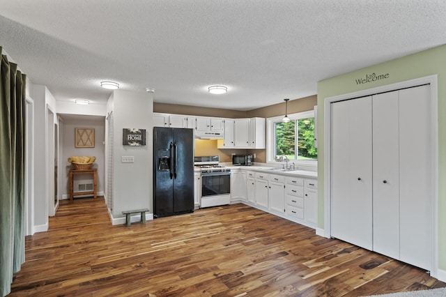 18125 Fillmore St NE, East Bethel, MN 55011 - kitchen featuring white range with gas cooktop, black fridge, dark wood finished floors, under cabinet range hood, and white cabinets