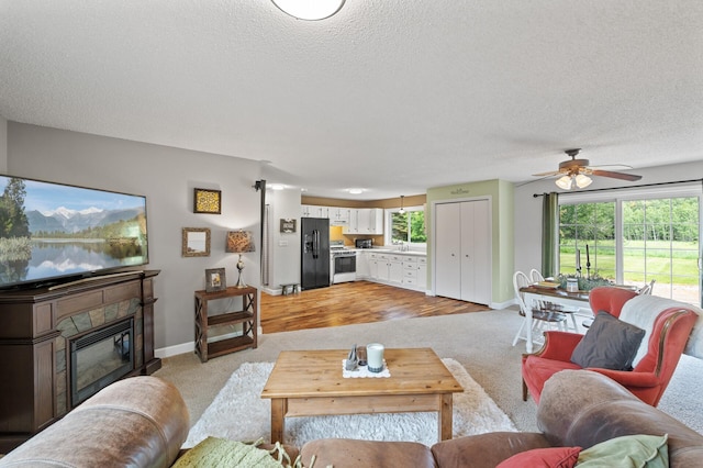 18125 Fillmore St NE, East Bethel, MN 55011 - living area featuring light colored carpet, a textured ceiling, a ceiling fan, and a glass covered fireplace
