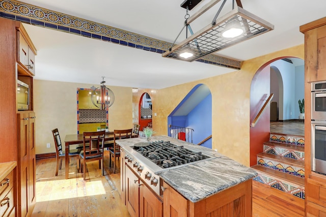 1919 Timberline Spur, Minnetonka, MN 55305 - kitchen with stainless steel gas cooktop, light wood-style floors, a chandelier, a center island, and arched walkways