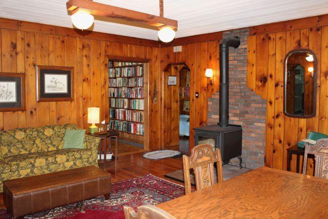 32704 310th Ln, Aitkin, MN 56431 - living room featuring wood walls, a wood stove, wood finished floors, and arched walkways