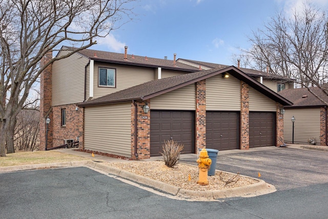 2436 Mendelssohn Ln N, Golden Valley, MN 55427 - view of front of home featuring brick siding, a garage, asphalt driveway, roof with shingles, and a chimney