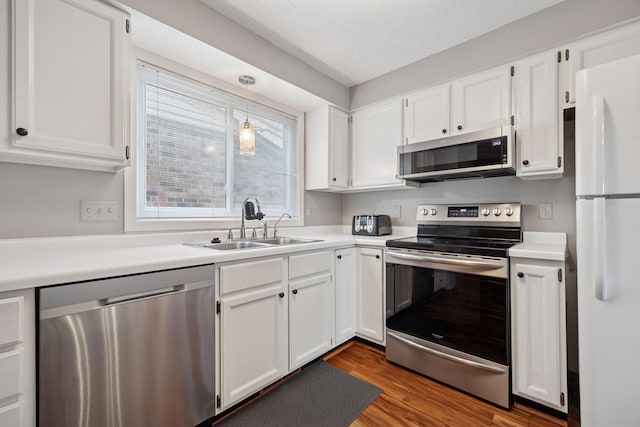 2436 Mendelssohn Ln N, Golden Valley, MN 55427 - kitchen with stainless steel appliances, a sink, white cabinetry, light countertops, and dark wood-style flooring