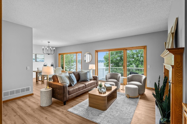 3868 Green Heights Trl SW, Prior Lake, MN 55372 - living room with a textured ceiling, a chandelier, light wood finished floors, and a fireplace with raised hearth
