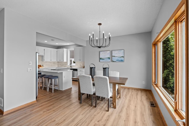 3868 Green Heights Trl SW, Prior Lake, MN 55372 - dining area featuring a chandelier, light wood-style floors, plenty of natural light, a textured ceiling, and recessed lighting