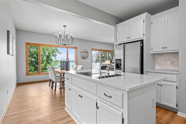 3868 Green Heights Trl SW, Prior Lake, MN 55372 - kitchen with stainless steel fridge with ice dispenser, black electric stovetop, a chandelier, white cabinetry, and light wood finished floors