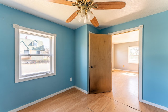 25 4th Ave, Soudan, MN 55782 - unfurnished bedroom with light wood-style flooring, multiple windows, and baseboards